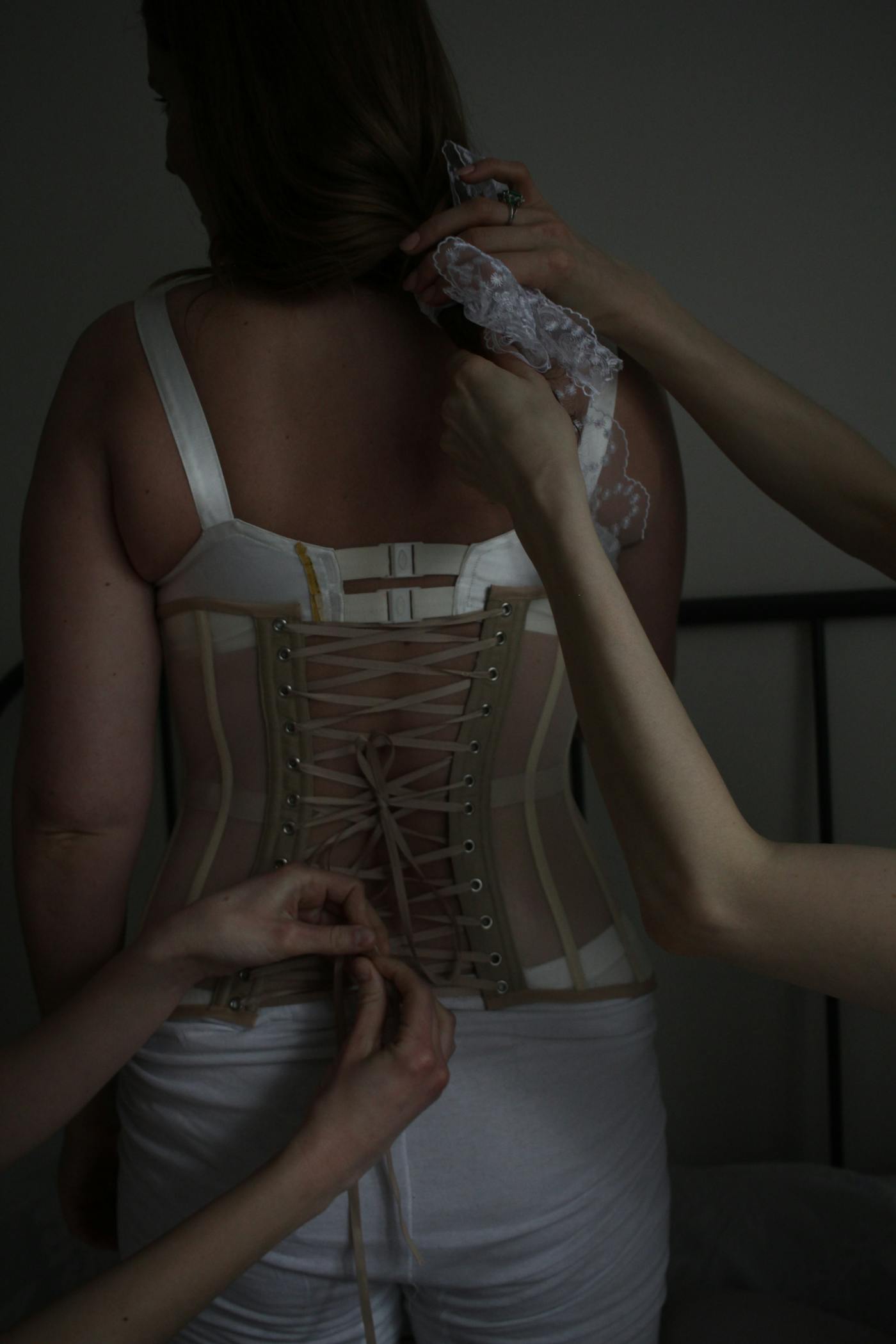 Hands tying lace on a corset close up